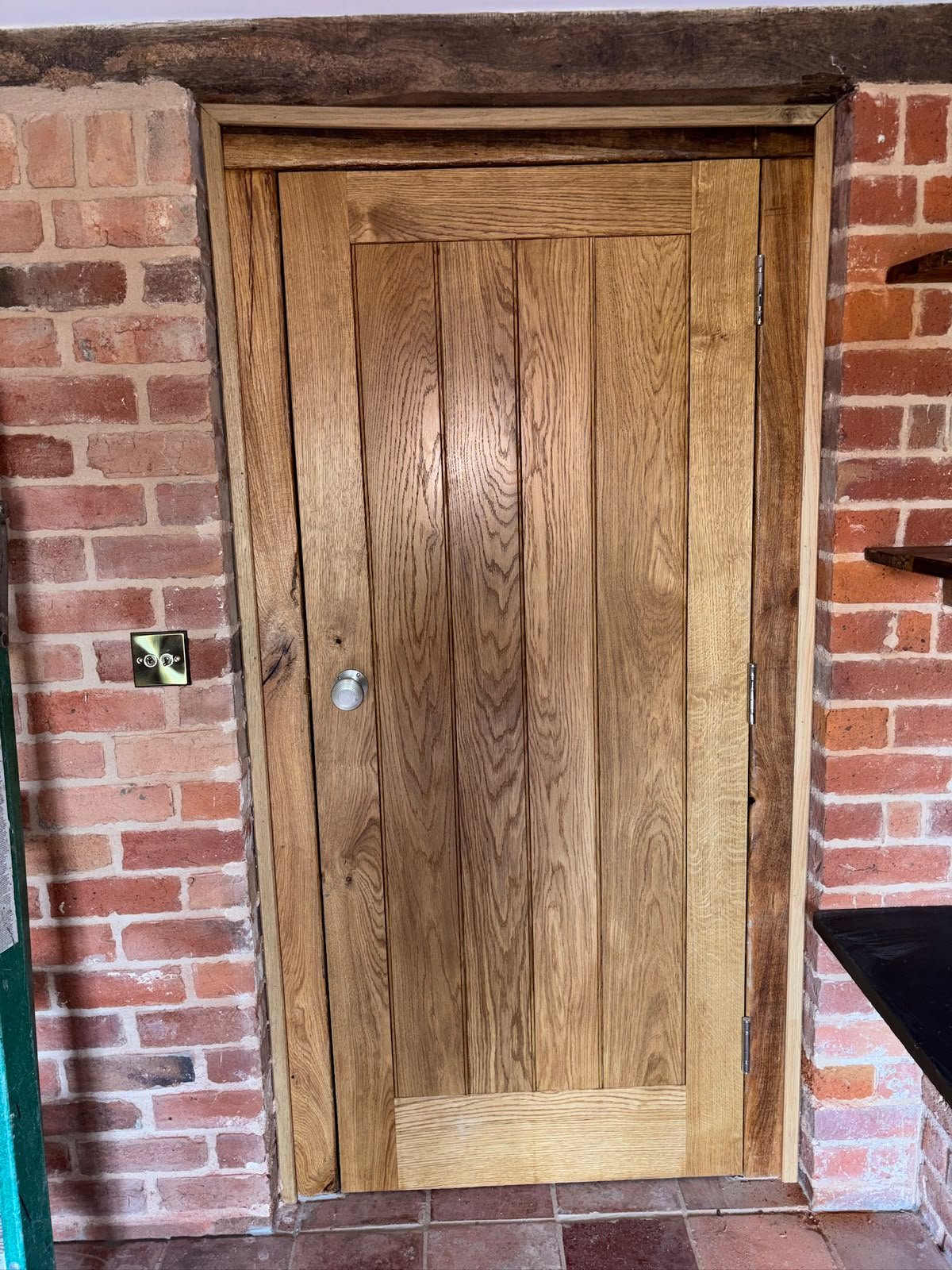 Solid oak internal door in a barn conversion with brick and beam surround