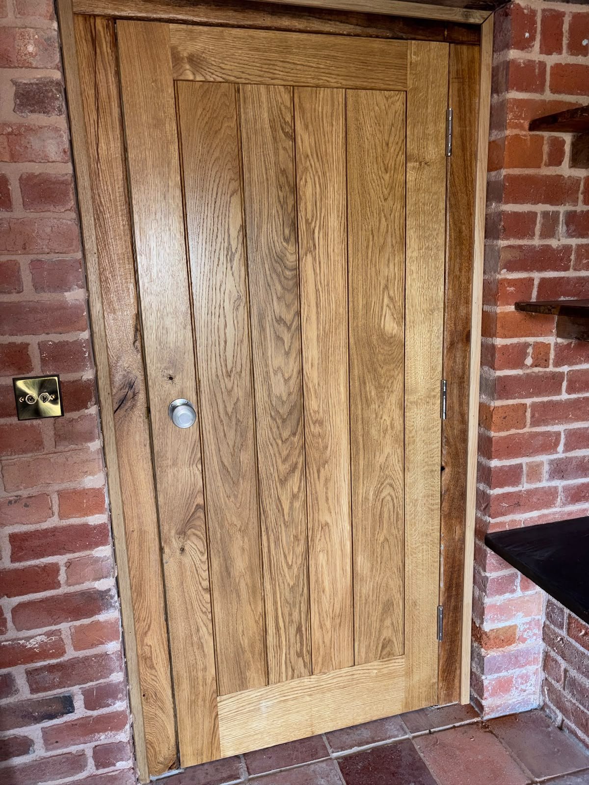 Solid oak internal door set into an exposed brick wall